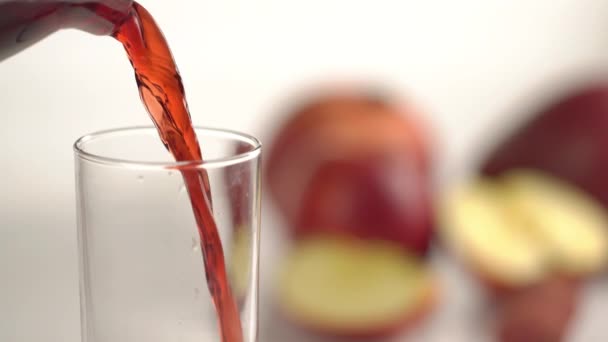 Η υψηλή ταχύτητα της το κόκκινο ποτό που ξεχύνεται στην υψηλή γυαλιού στο φόντο των μήλων. Προβολή με μεγέθυνση. — Αρχείο Βίντεο