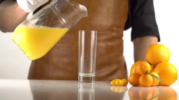 Апельсиновый напиток наливается из графина в высокий стакан плитой. Фруктовый состав состоял из апельсинов . — стоковое видео
