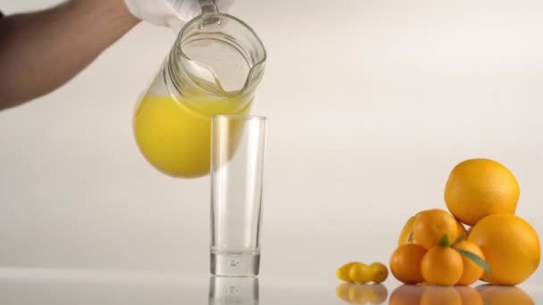 La composizione della frutta consisteva nelle arance e mandarini posti vicino al bicchiere vuoto che si riempivano con il succo d'arancia. . — Video Stock