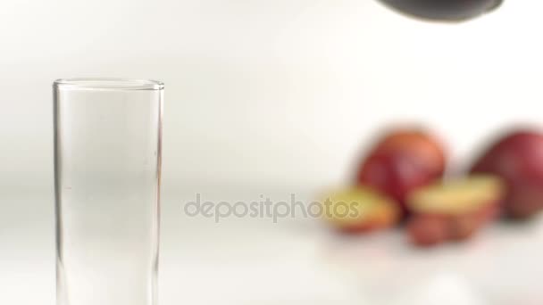 Il ripieno del bicchiere alto con il succo rosso sullo sfondo sfocato della composizione del frutto consisteva delle mele. . — Video Stock