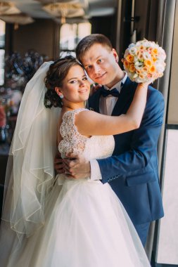 Romantik mutlu çift, damat gelini pencere portre yakınındaki kucaklayan