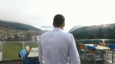 Balkon çit için gidiş ve orman ve nehir manzarasına zevk adam arkadan görünüm.