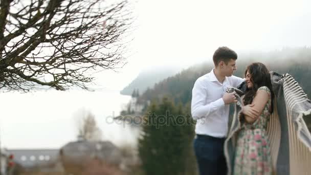 Mannen inslagning den vackra flickan i Pläden på bakgrunden till bergen. — Stockvideo