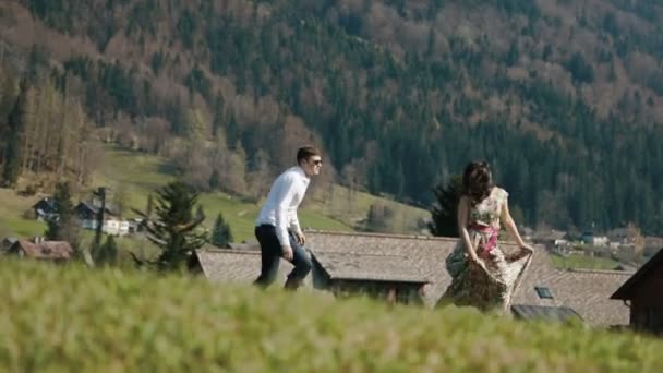 En närbild av det lyckliga paret kör i bergen på bakgrunden till den sutic trä hus. — Stockvideo