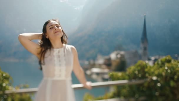 A vista de perto da menina no vestido vintage classificando seu cabelo no fundo da antiga cidade fluvial nas montanhas . — Vídeo de Stock