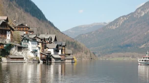 La composición del barco de natación cerca de la pequeña ciudad situada en la orilla de las montañas . — Vídeos de Stock