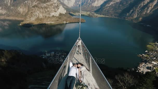 A vista acima do casal que jaz na torre sob o rio cercado pelas montanhas . — Vídeo de Stock