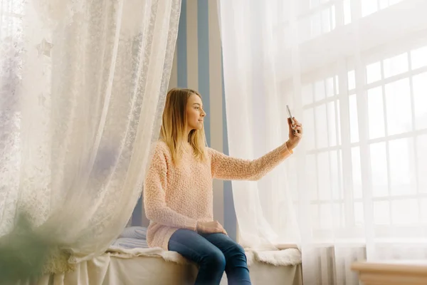 십 대 동안 침대에 앉아 전화를 통해 selfie를 복용의 수평 사진. — 스톡 사진