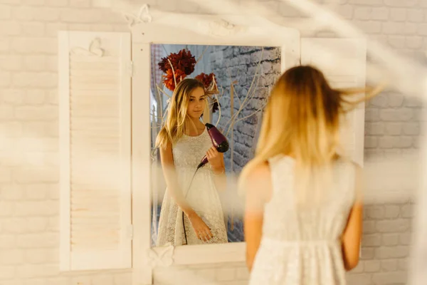 Odraz v moderní zrcadlo teenagera, sušení vlasů. — Stock fotografie