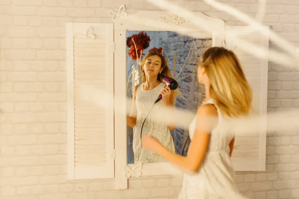 The reflection of the blond teenager drying her hair. — Stock Photo, Image