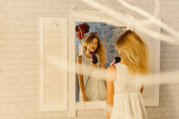 The girl is singing while drying the hari. The reflection in the modern mirror. — Stock Photo, Image