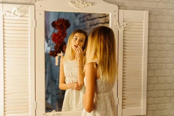 The young teenager is applying the lips in the mirror. The close-up reflection. — Stock Photo, Image