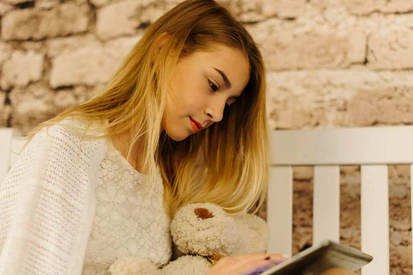 Blond dospívající dívka drží na tabletu a medvídek. Detailní zobrazení. — Stock fotografie