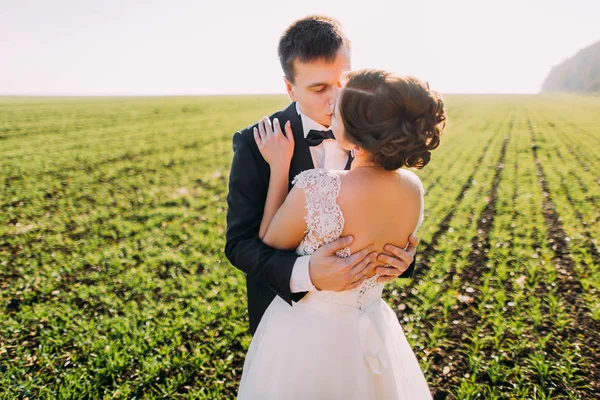 A visão de close-up dos recém-casados beijando no campo verde . — Fotografia de Stock