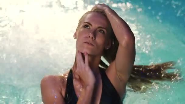 The sexy woman is sorting the hair while posing in the pool. — Stock Video