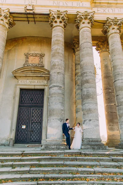 Ganzkörperansicht des Brautpaares, das in der Nähe der Säulen des antiken Gebäudes steht. — Stockfoto