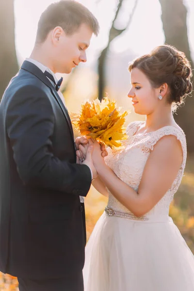 Retrato vertical sensível dos recém-casados. A noiva segura o buquê de folhas amareladas . — Fotografia de Stock