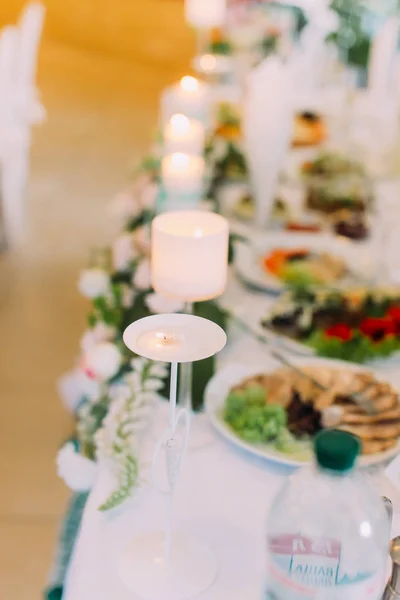 A vista vertical close-up da vela no fundo borrado da comida no conjunto de mesa de casamento . — Fotografia de Stock