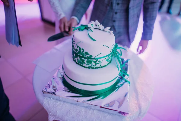 El pastel de boda blanco con cintas verdes colocadas sobre la mesa . —  Fotos de Stock