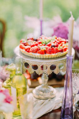 Düğün meyve kek kiraz ve çilek ile dekore edilmiştir. Bu romantik mum ve şarap ile çevrili kurulu kek üzerine yerleştirilir.