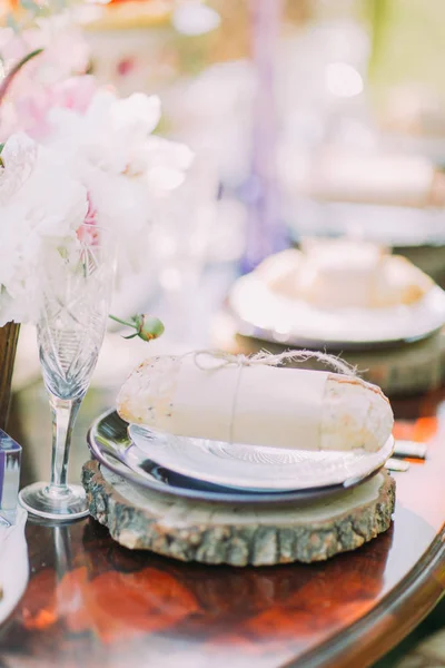 A foto vertical lateral do ajuste da mesa de casamento. O pão embrulhado em papel artesanal e corda está localizado no suporte de madeira sob a placa . — Fotografia de Stock