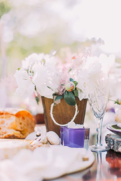 Bílé květy v dřevěné nádoby poblíž svíce na rozostřeného pozadí. — Stock fotografie