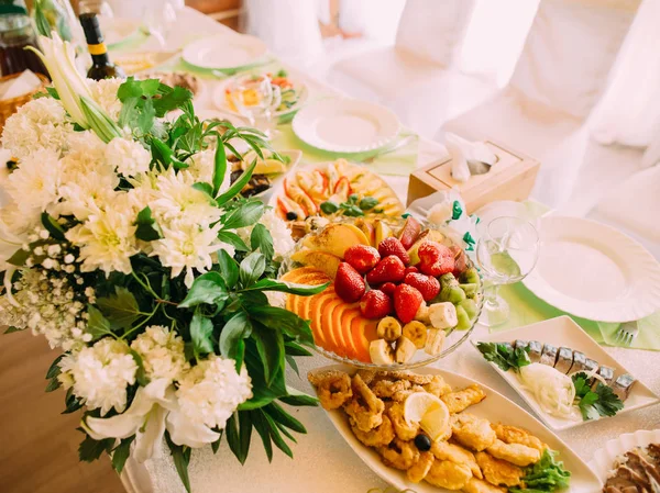 Die obige Ansicht der Früchte und verschiedenen Gerichte, die auf dem Hochzeitstisch neben dem riesigen weißen Strauß platziert wurden. — Stockfoto