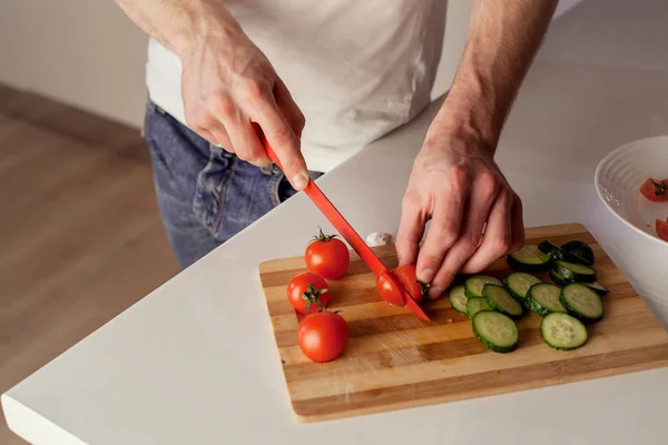 A man cutting food on a wooden board.