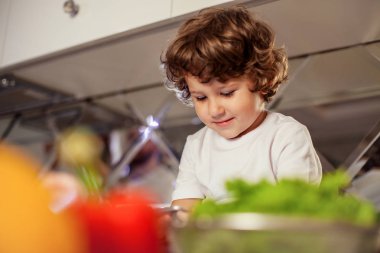 Mutfakta, oturma ve bir telefon onun elinde tutan küçük çocuk gülümsedi.