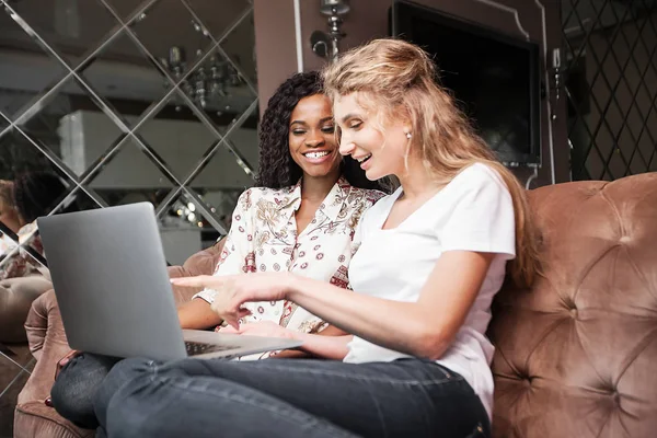 Twee gelukkige vrouwen zit op de Bank met de laptop. — Stockfoto