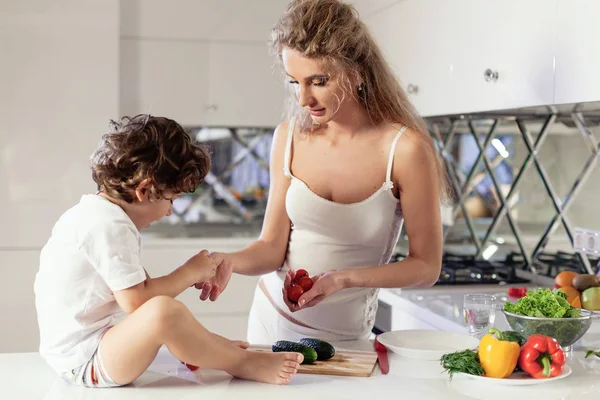 Attractive young woman with her little son cooking something in the kitchen. — Stock Photo, Image