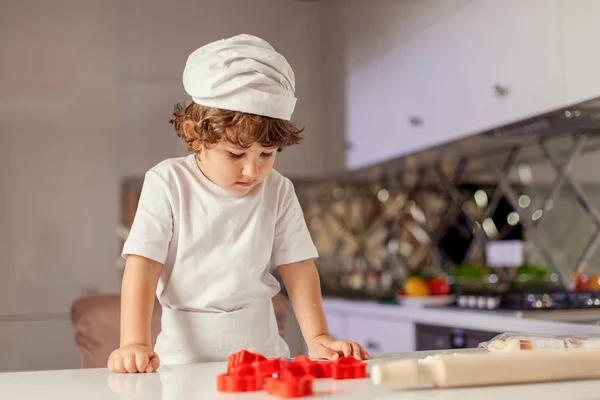 Small cute boy looking at the table with baking stuff. — Stock Photo, Image