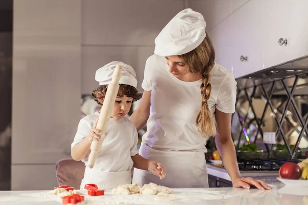 Young mother baking together with her little son in the modern white kitchen. — Stock Photo, Image