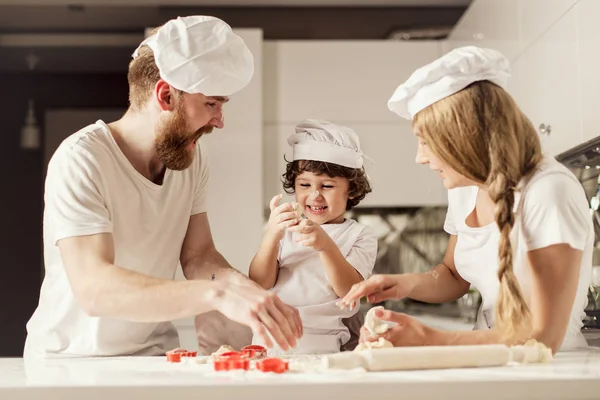 Happy family of parents and little son making figures of dough. — Stock Photo, Image