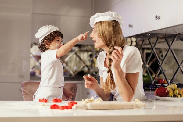 Mother making a dough for baking cookies together with her little son. — Stock Photo, Image