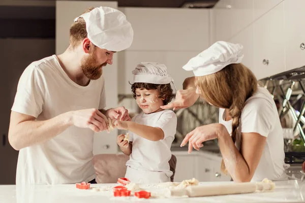 Mother, father and little son playing with the flour and red baking forms. — Stock Photo, Image