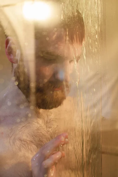 Retrato de un hombre guapo y triste duchándose. Concéntrate en un vaso . — Foto de Stock