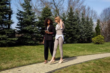 Yürüyüş ve konuşmayı iki ciddi çekici iş kadınları. Bir womam siyah.