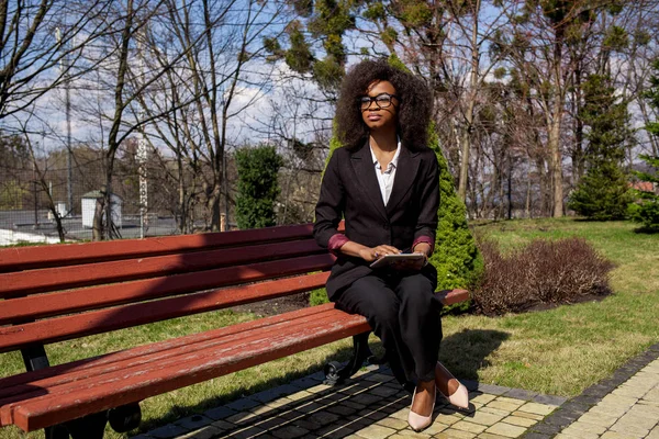 Krásná černá žena pomocí tabletového počítače. Podnikatelka na sobě oblek, afro účes. — Stock fotografie