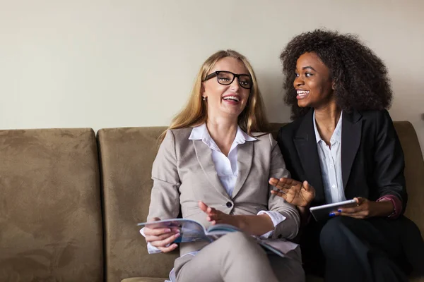 Gelukkig aantrekkelijke vrouwelijke ondernemers op de bank zitten en praten. — Stockfoto