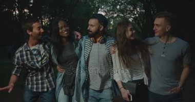 Beş çok kültürlü hipster arkadaşlar yakın görünümünü gülüyor ve akşam parkta yürüyüş sırasında sarılma.