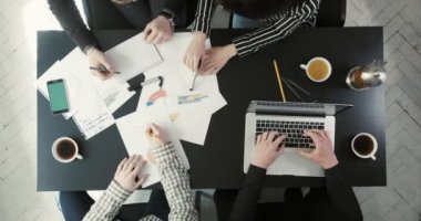 Eller iş zamanlamaları ve grafik holding, dizüstü bilgisayarda yazarak ve çay içme dört kişi yukarıdaki görünümü. İş kompozisyon.