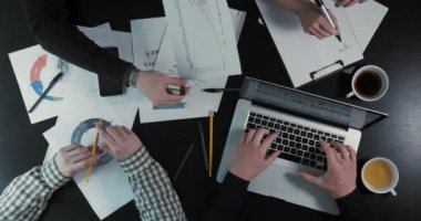 Dizüstü bilgisayarda yazarak, grafik gösterilen ve zamanlamayı not defterinde yazılı işadamları el görünümünün üzerinde yakın çekim.