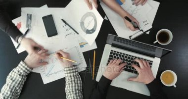 Grafik, dizüstü bilgisayar ve cep telefonu kullanarak iş sorunları çözme işadamları görünümünü yukarıda yakın çekim.