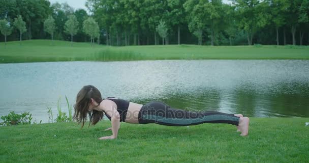 La mujer muy delgada está haciendo flexiones en el fondo del río . — Vídeos de Stock