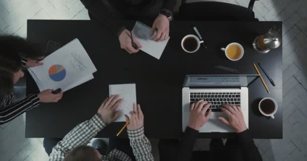 Los trabajadores están garabateando mientras el jefe está resolviendo los problemas de negocio utilizando gráficos. El hombre de negocios está escribiendo en el portátil . — Vídeos de Stock