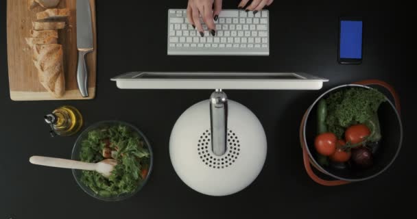 Ovanifrån på den mans händer att skriva på hans dator nära maten. — Stockvideo