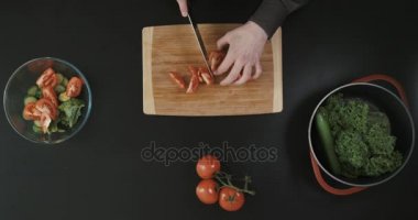 Adam kesme domates yakınındaki diğer sebze ahşap kesme tahtası üzerinde. Üstten Görünüm.
