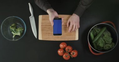 Üstten Görünüm. Elle kesme tahtası üzerinde telefon. Sebze ve yakın yerleştirilen bıçak.