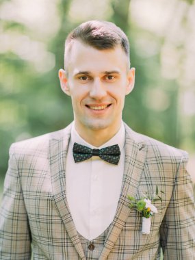 Park arka plan, gülümseyen damat dikey portresi.